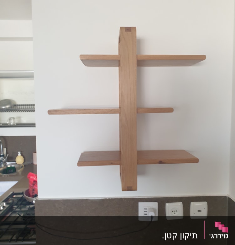 מדף עץ מותקן על קיר לבן עם שקעי חשמל